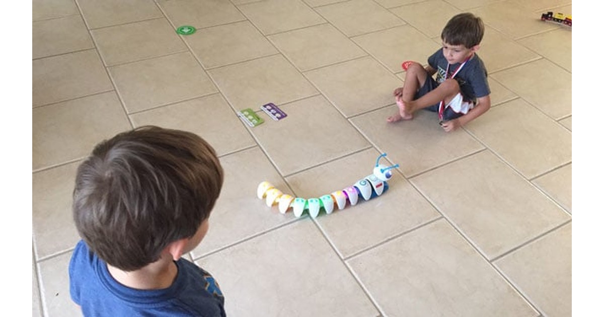 Code-a-pillar completo con varios segmentos conectados sobre un suelo de baldosas durante una actividad con niños.