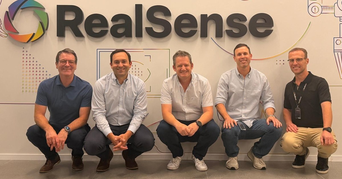 Fotografía cedida por RealSense de cinco representantes de RealSense y Cognex ante el logotipo de RealSense.