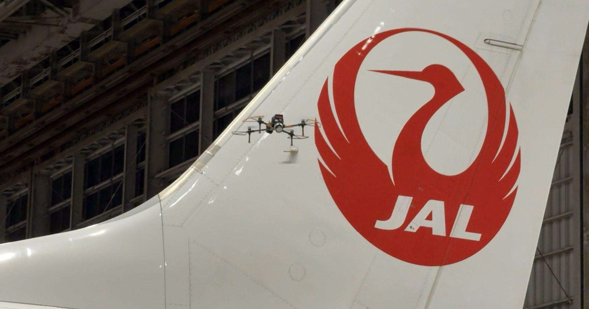 Fotografía oficial del dron Iris GVI de Donecle volando junto a la cola de un avión de Japan Airlines dentro de un hangar.