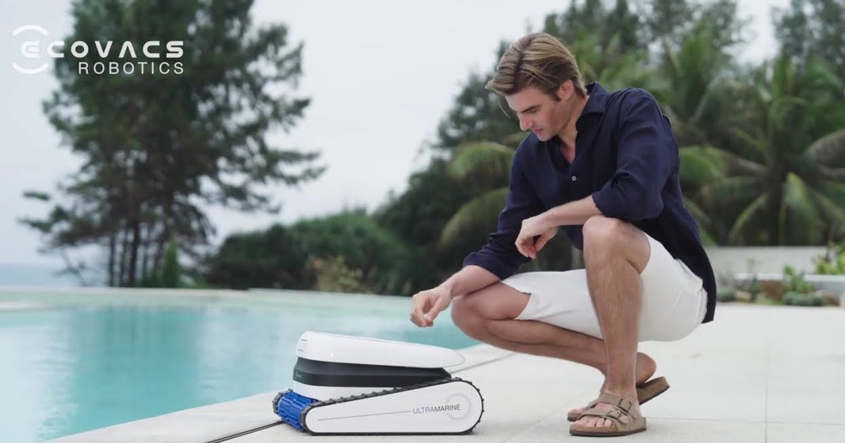 Fotograma oficial de una persona junto a un ECOVACS Ultramarine P1 blanco y azul, con la tapa levantada, en el borde de una piscina.