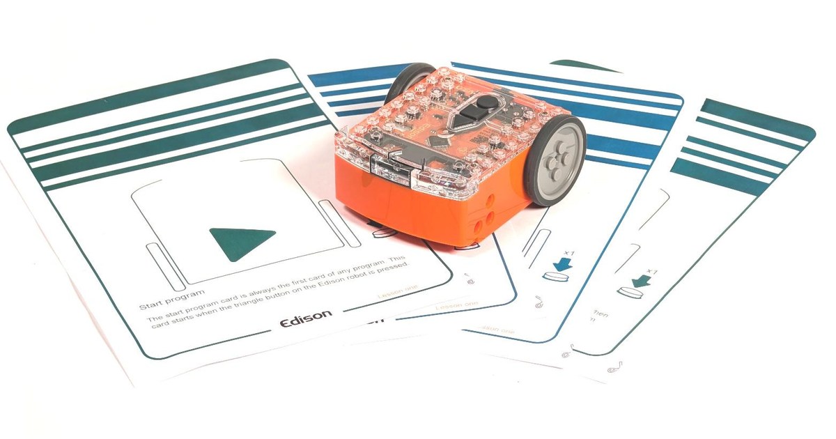 Fotografía oficial de Edison V3, con carcasa naranja y cubierta transparente, sobre tarjetas de programación con códigos de barras.