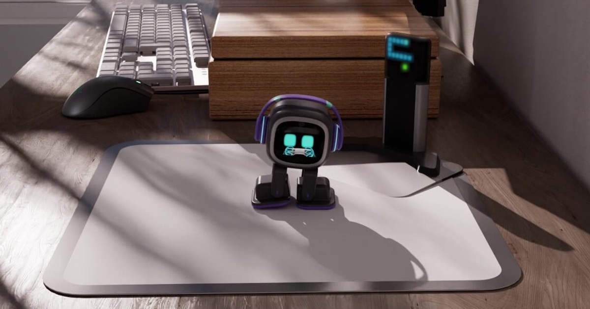 Frame oficial de EMO sobre una alfombrilla blanca en un escritorio de madera, con Home Station detrás y un teclado al fondo.