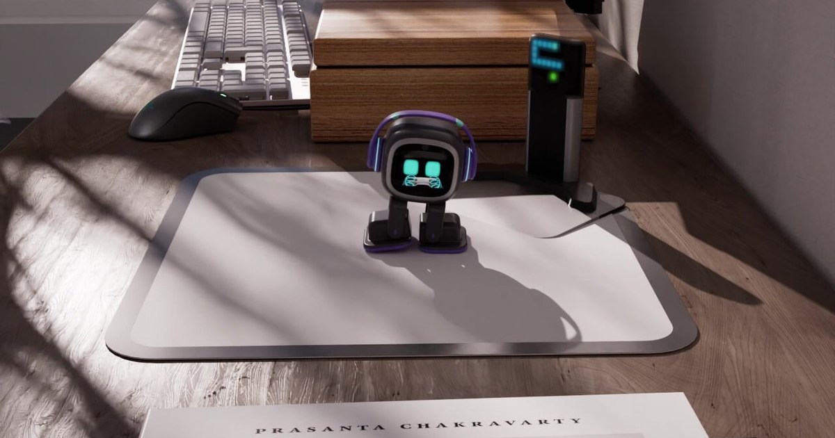 EMO sobre su alfombrilla junto a la Home Station en un escritorio de madera, imagen del vídeo promocional oficial de LivingAI.