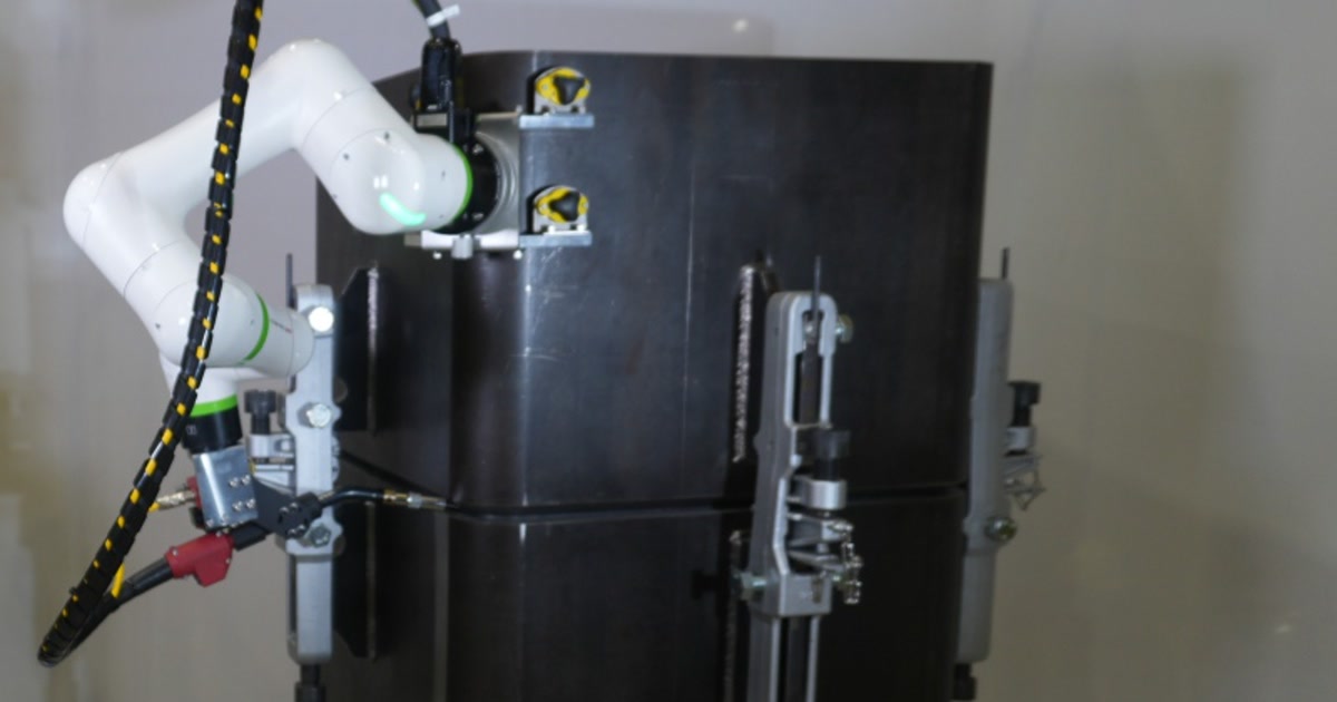 Fotografía oficial de un FANUC CRX-3iA fijado a una columna de acero, con la antorcha orientada hacia la junta horizontal.