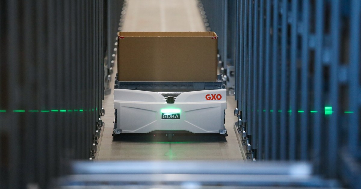 Un robot Skypod blanco de GXO transporta una caja entre estanterías del almacén de Guess en Venlo, en una fotografía oficial de Exotec.