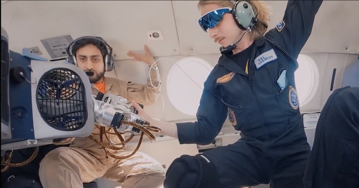 JOY, con un ventilador protegido por una rejilla y un brazo extendido, junto a dos participantes dentro del avión de pruebas; imagen oficial de Icarus Robotics.