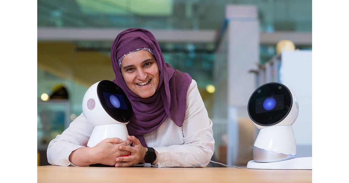 La investigadora Sharifa Alghowinem junto a dos robots Jibo sobre una mesa del MIT; el robot de la derecha aparece completo.