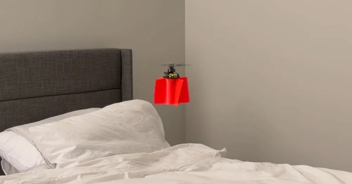 Frame del vídeo de Joshua Bird: su pequeño dron rojo de una hélice vuela sobre una cama, junto al cabecero.