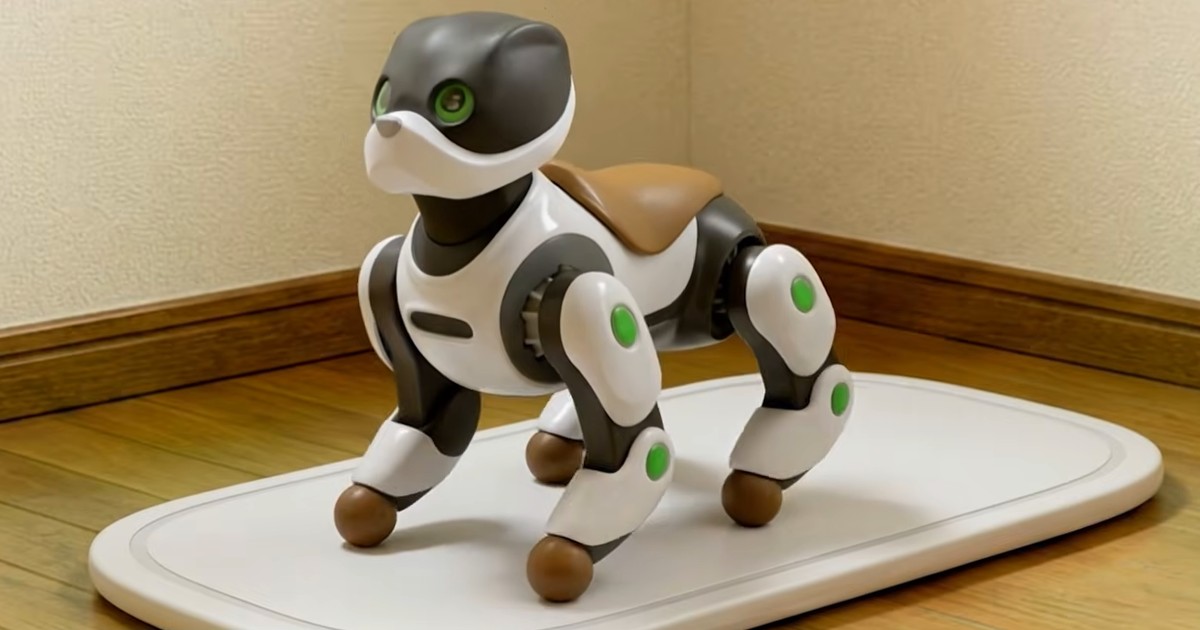 Fotograma del vídeo promocional oficial de Kawasaki que representa a Home LEO, un robot de cuatro patas blanco y negro con ojos verdes, sobre una plataforma de carga.