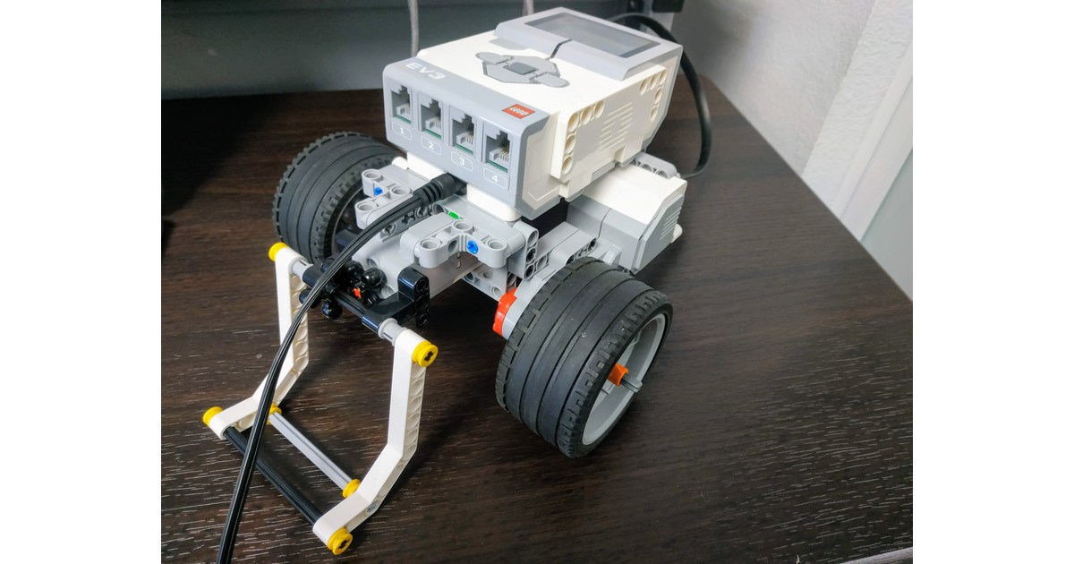 Robot LEGO EV3 de ruedas con una pinza frontal sobre una mesa.