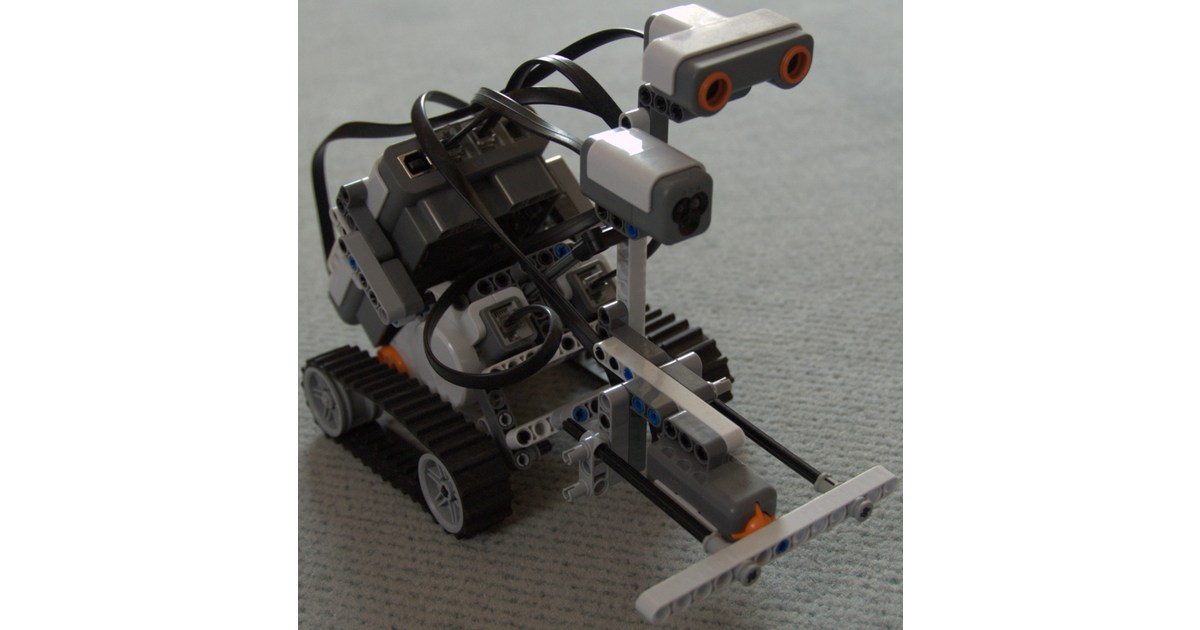 Construcción LEGO NXT 2.0 sobre orugas con sensores y mecanismo frontal visibles.