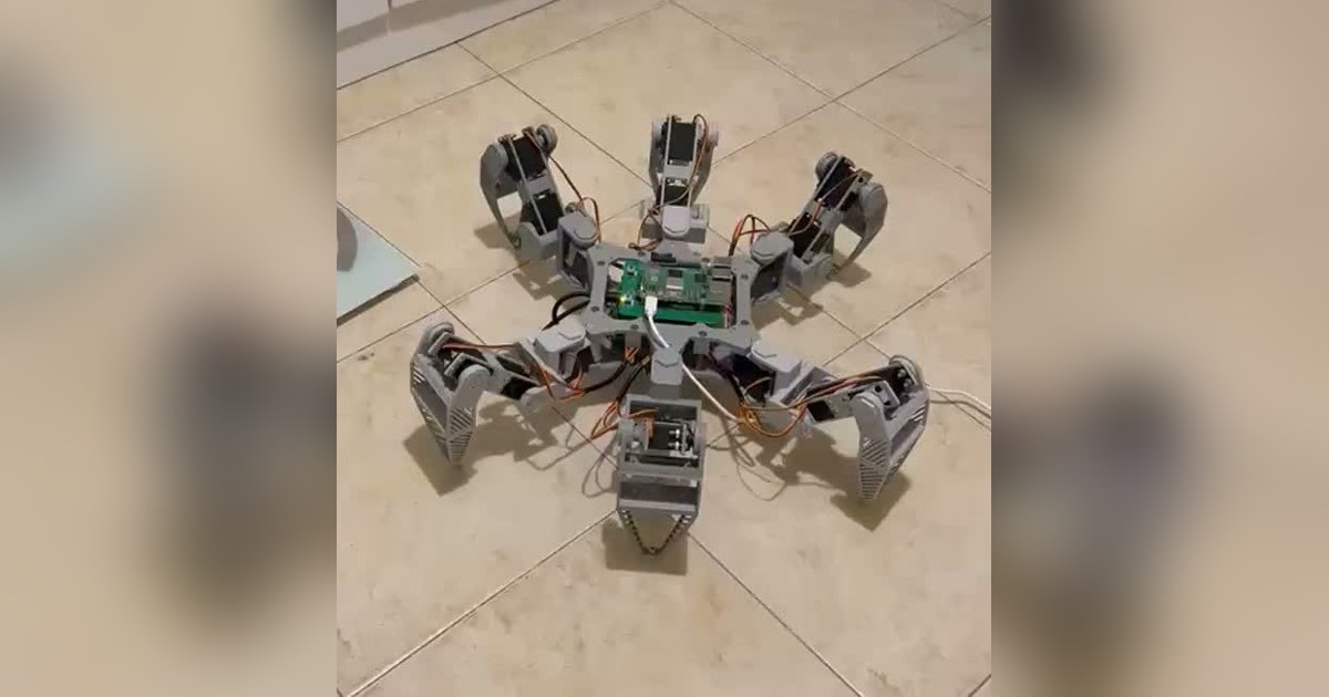 Fotograma recortado del inicio del vídeo de mike-tr, con el hexápodo completo de seis patas grises sobre suelo claro.
