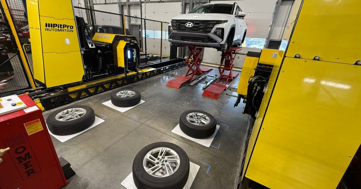 Fotografía del sistema PitPro instalado a ambos lados de un coche elevado en un taller, con cuatro ruedas preparadas en el suelo.