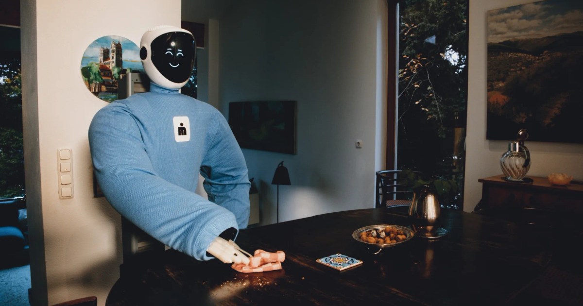 Fotografía oficial de Plim con cubierta azul y rostro luminoso, pasando un paño sobre una mesa de comedor con una de sus pinzas.