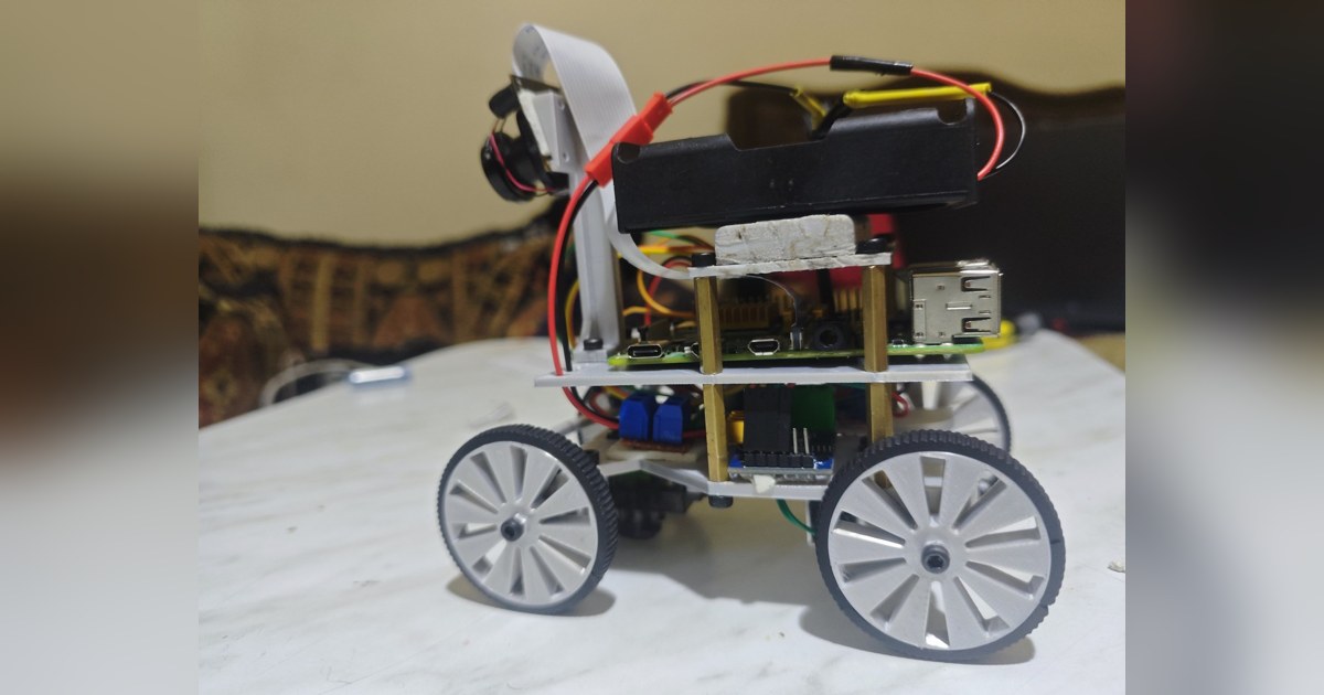 Fotografía de The Red Castle de su coche robot completo visto de lado, con cuatro ruedas grises, cámara elevada y chasis de varios niveles.