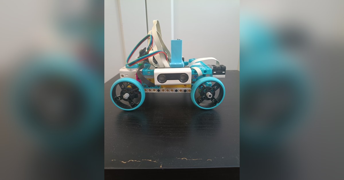 Fotografía de RoboTronics Bilbao de su coche robot completo visto de lado, con piezas claras y azules, cuatro ruedas y sensores visibles.