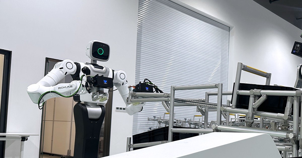 Fotografía oficial de ROKAE: un robot Helios blanco, con dos brazos y pinzas, junto a una línea de montaje en la fábrica de Schaeffler en Taicang.
