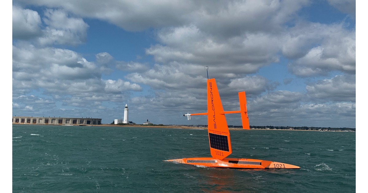 Saildrone Explorer naranja identificado como SD 1021 navegando por el mar con su vela rígida.
