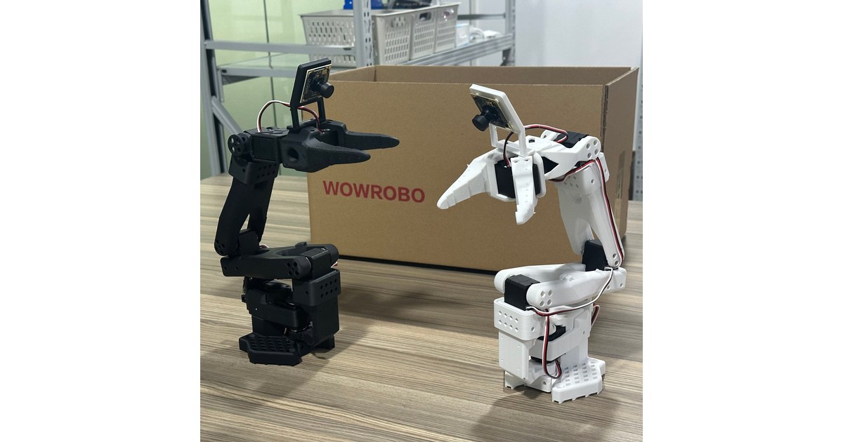 Dos brazos SO-ARM100 completos, uno negro y otro blanco, fotografiados junto a una caja WowRobo.