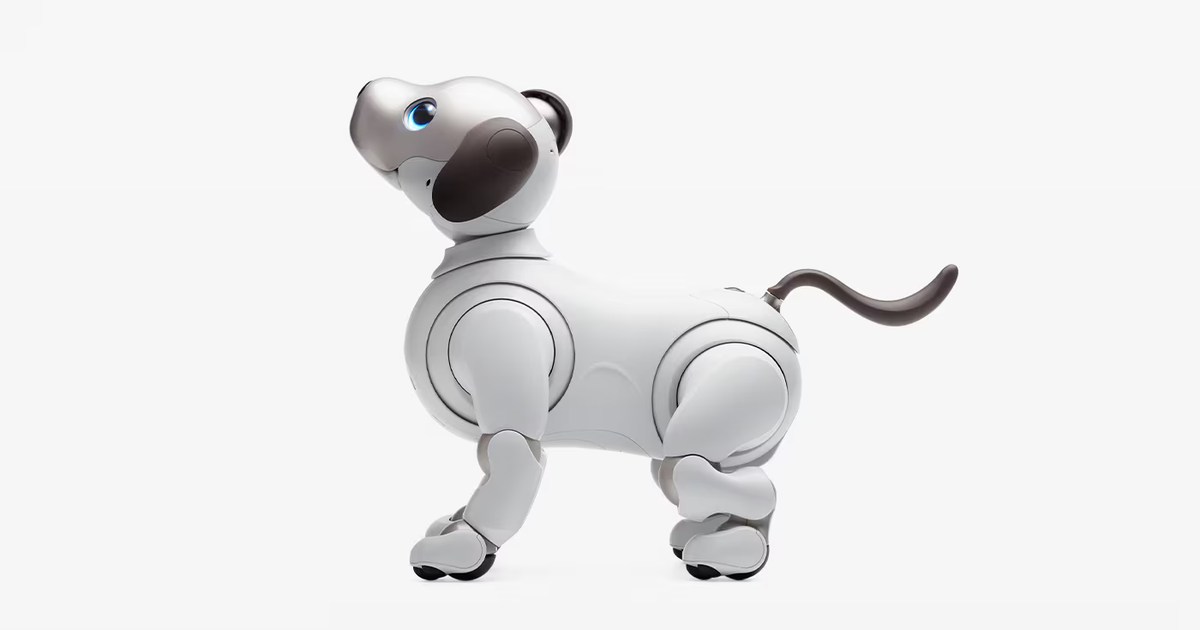 Imagen oficial de Sony aibo ERS-1000 blanco, de perfil, con la cabeza levantada y la cola curvada sobre un fondo claro.