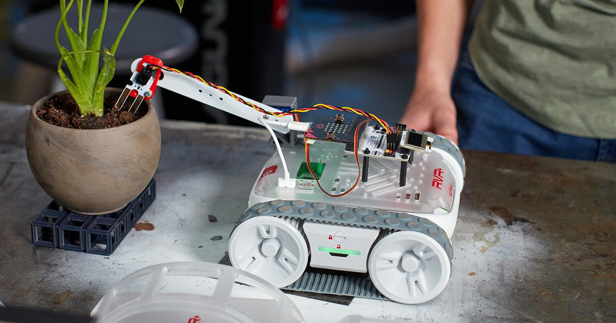 Fotografía oficial de un Sphero RVR+ con una micro:bit y ampliaciones montadas sobre el chasis, junto a una maceta.