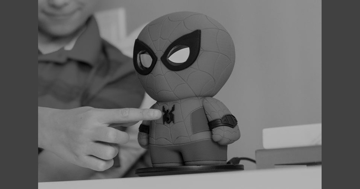 Fotografía oficial en blanco y negro del Spider-Man interactivo de Sphero sobre su base, mientras una persona pulsa el botón del pecho.