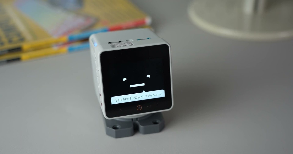 Fotograma del tutorial oficial de M5Stack con un StackChan blanco sobre una mesa, mostrando ojos, boca y una respuesta de texto con el software de fábrica.