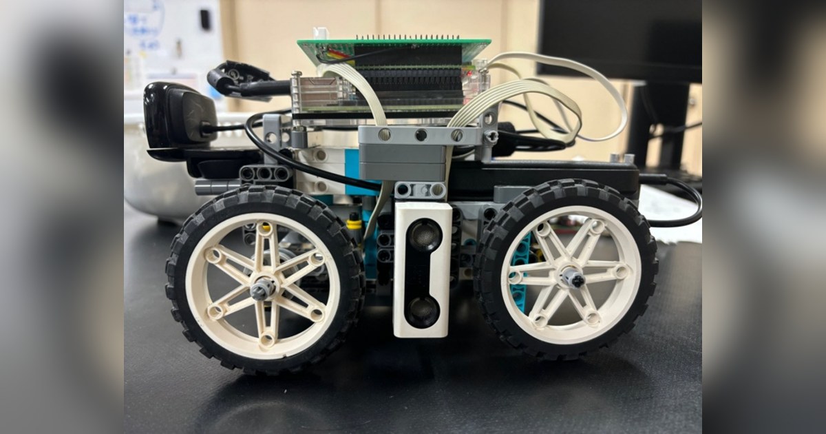 Fotografía de Teikyo RoboLet’sGo de su coche robot completo visto de lado, con piezas LEGO, cuatro ruedas y electrónica sobre el chasis.