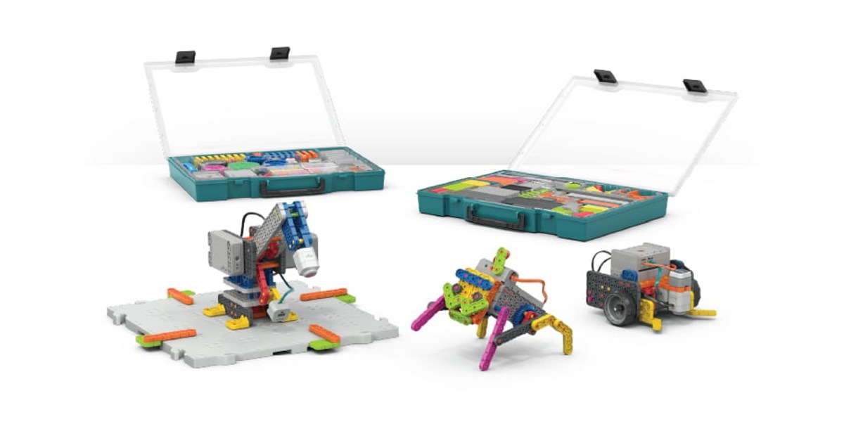 Fotografía oficial de tres montajes de VEX GO, incluido el robot de ruedas Code Base, delante de dos cajas abiertas de piezas.