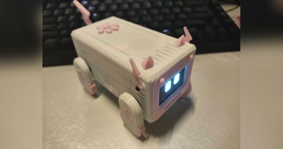 Fotografía del constructor de Xiaozhi ESP32 Pet completo, con carcasa rosa, pantalla facial y cuatro patas, sobre un escritorio.