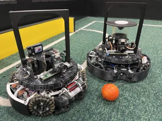 Fotografía del equipo AIR de dos ejemplares completos de su robot de fútbol de 2026, con ruedas omnidireccionales y sensores.