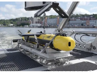 Sistema submarino KATFISH amarillo apoyado en su equipo de lanzamiento y recuperación sobre la cubierta de un barco.