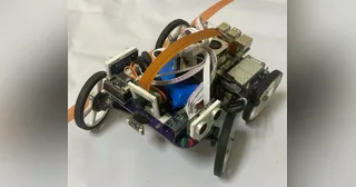 Fotografía de The Pythons de su coche robot completo, con placa estructural, cuatro ruedas y soporte elevado de cámara.