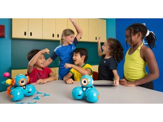 Fotografía oficial de dos robots Dash azules de Wonder Workshop sobre una mesa durante una actividad con niños.