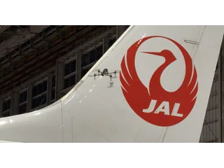 Fotografía oficial del dron Iris GVI de Donecle volando junto a la cola de un avión de Japan Airlines dentro de un hangar.