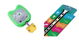 Composición de fotografías oficiales: Mai-Z junto a la placa amarilla Screen-Free, con una flecha que indica dónde insertarla, y una secuencia de tarjetas de programación.