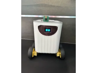 Fotografía de cyrixninja de Mizuna completo, con cuerpo de caja blanca, cuatro ruedas, cara OLED y cámara sobre el cuerpo.