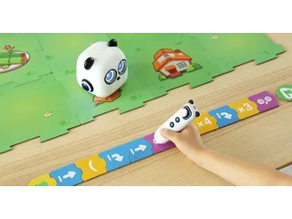 Imagen promocional oficial de mTiny sobre un mapa verde, con una mano utilizando el lápiz lector sobre una secuencia de tarjetas de programación.