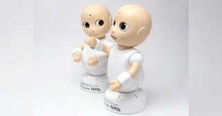 Dos robots CommU blancos de sobremesa con ojos y cabeza articulados.