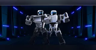 Dos humanoides Robosen de la serie K1, blanco y gris oscuro, en una presentación del fabricante.