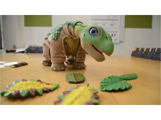 PLEO rb sobre una mesa del laboratorio de interacción humano-robot de la SDU, junto a sus hojas de juego.