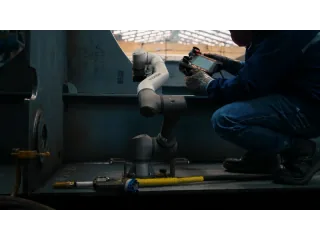 Robot de soldadura ArcLift GO de HD Hyundai trabajando junto a un operario dentro de una estructura de acero en un astillero.