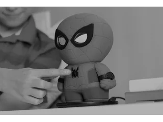 Fotografía oficial en blanco y negro del Spider-Man interactivo de Sphero mientras una persona pulsa su botón frontal.