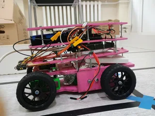 Fotografía de KU STEAM Pinkies de su coche robot completo visto de lado, con chasis rosa por niveles, cuatro ruedas y cableado visible.