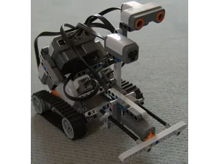Construcción LEGO NXT 2.0 sobre orugas con sensores y mecanismo frontal visibles.