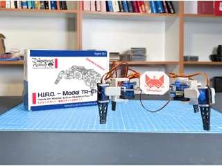Fotografía oficial de H.I.R.O. TR-01-A completo, con cuatro patas y cuerpo blanco, sobre una mesa de montaje con la caja del kit.