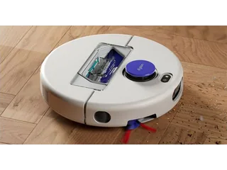 Fotografía oficial del robot aspirador blanco Dyson R1 Nurovi Dry recogiendo residuos sobre un suelo de madera.