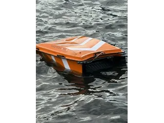 WasteShark Plus naranja navegando sobre el agua con la abertura de recogida frontal visible.