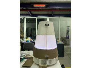 Fotografía de Nicolas Lara del robot completo, con cuerpo de madera y cubierta translúcida iluminada sobre su base móvil.
