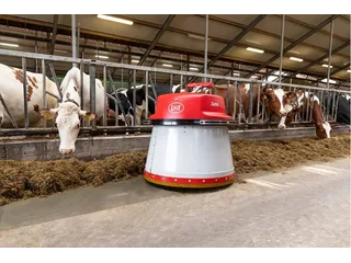 Lely Juno rojo y blanco junto al alimento y las vacas en un pasillo de la granja.